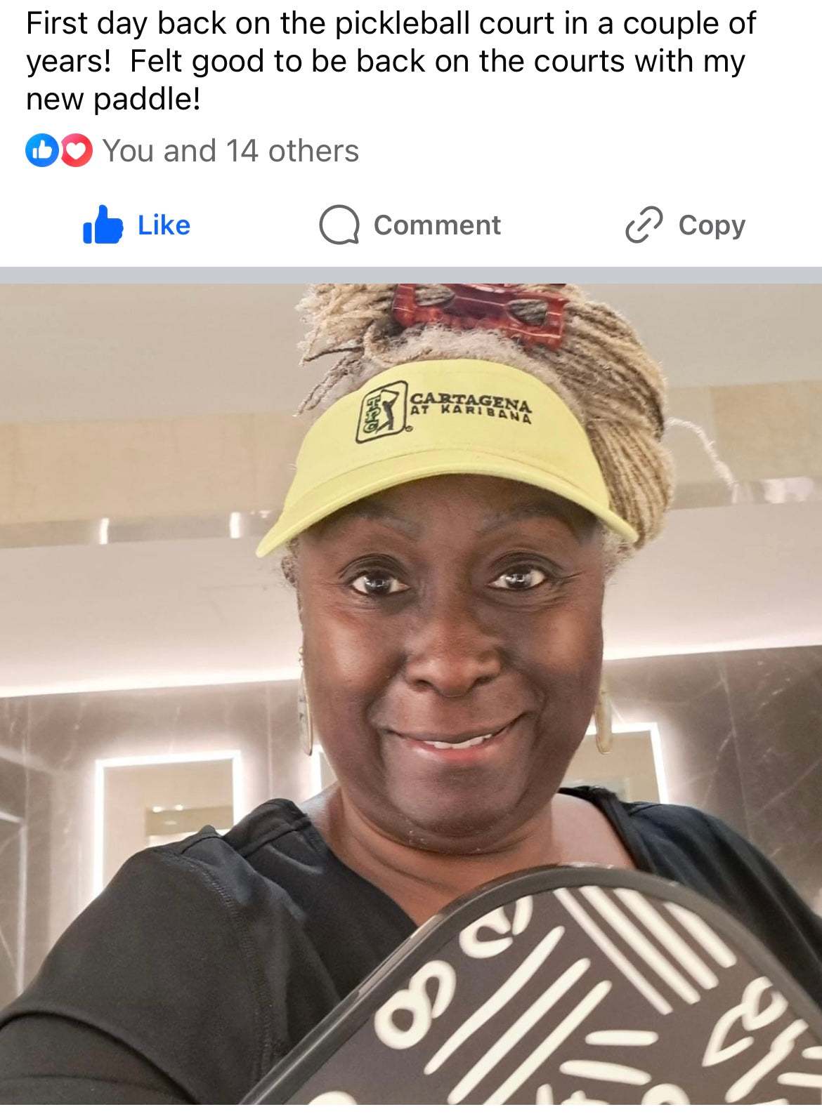 A smiling woman holds a pickleball paddle that she purchased from a Black woman owned business called Pickleblack. The woman's photo is set against social media comments explaning that she feels good to be back on the pickleball court.